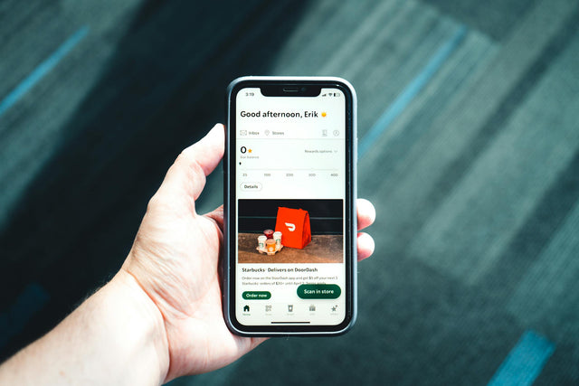 Hand holding phone with shopping app for buying kids clothes online