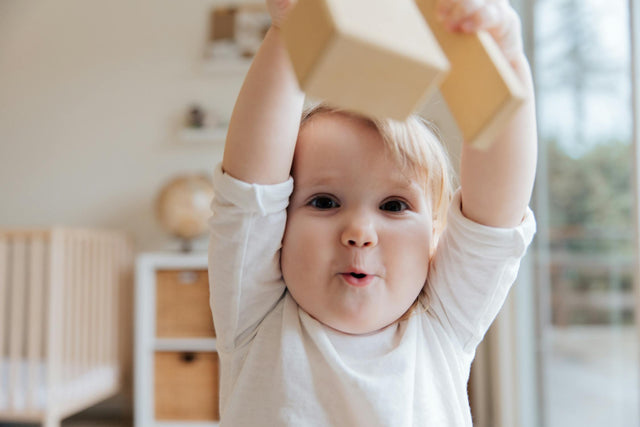 Adorable toddler in soft everyday outfit playing with toys
