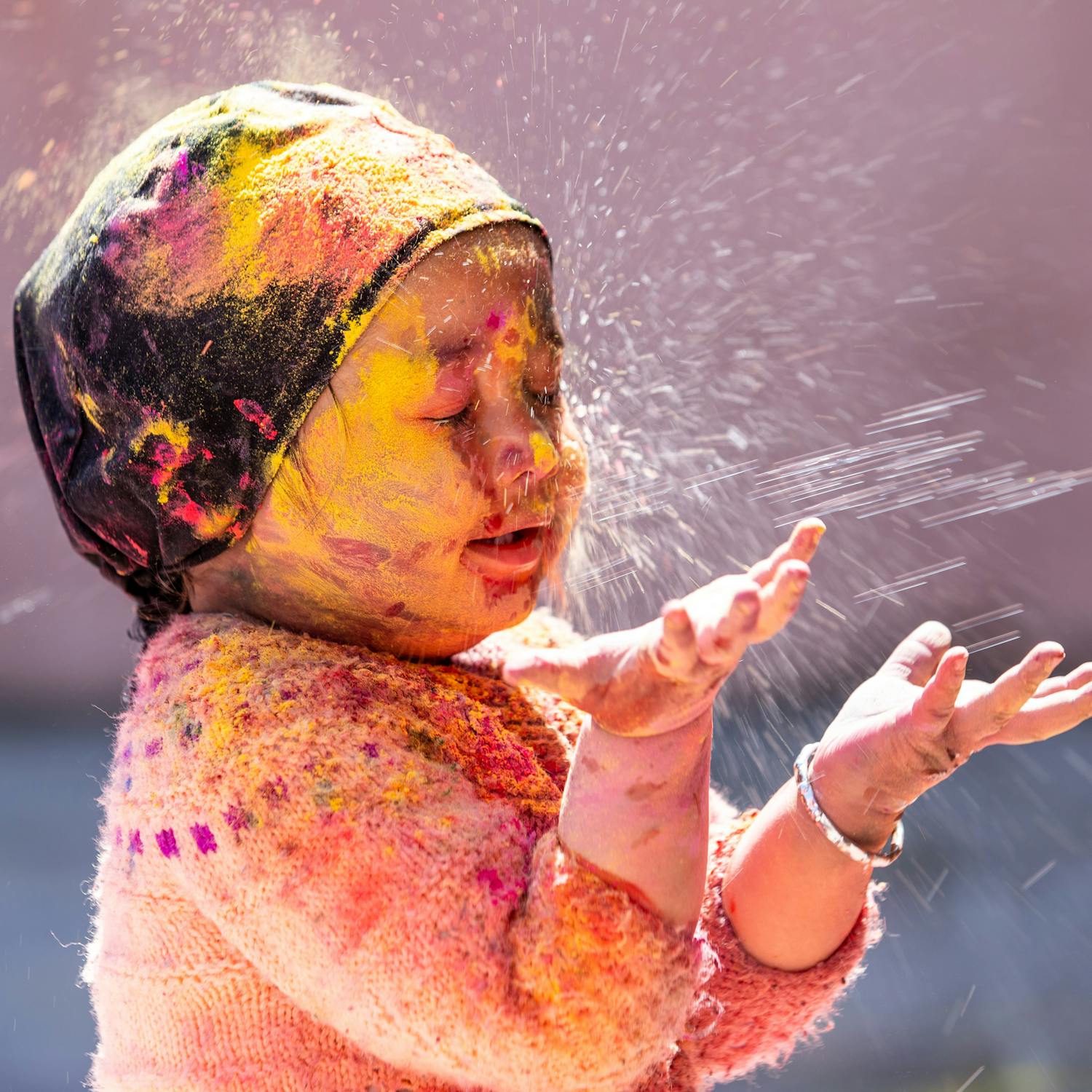 Adorable girl playing with bright Holi festival colors outdoors