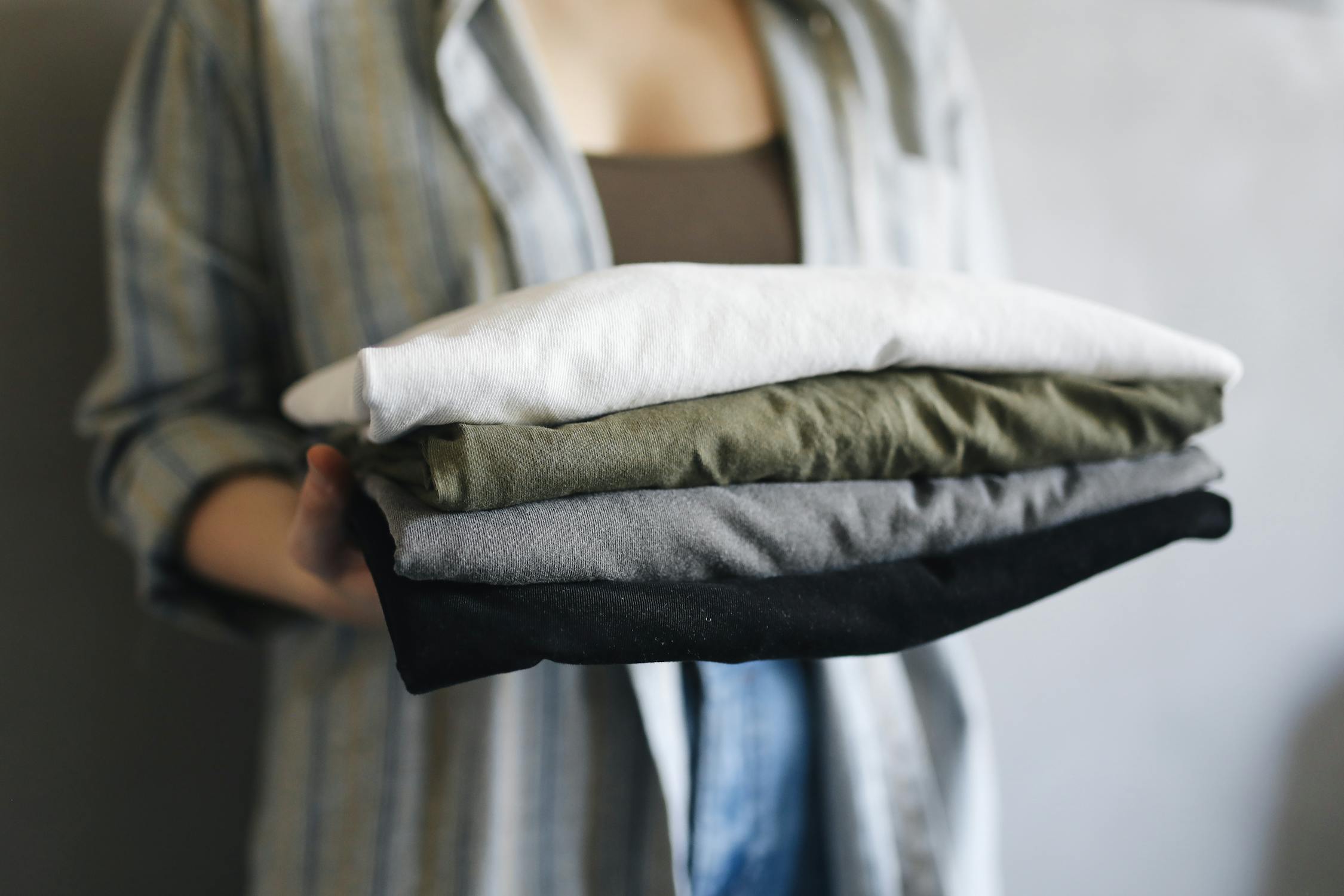 Person holding a stack of neatly folded premium quality kids shirts