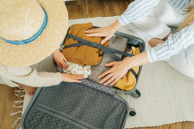 Woman and child packing clothes in suitcase for family vacation