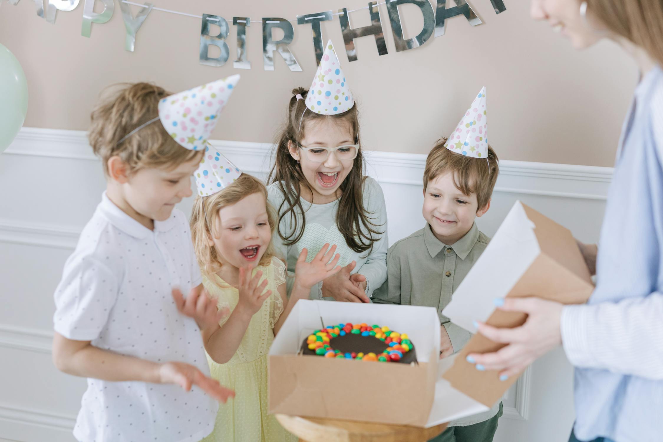 Happy kids celebrating first birthday with cake and pastel decorations